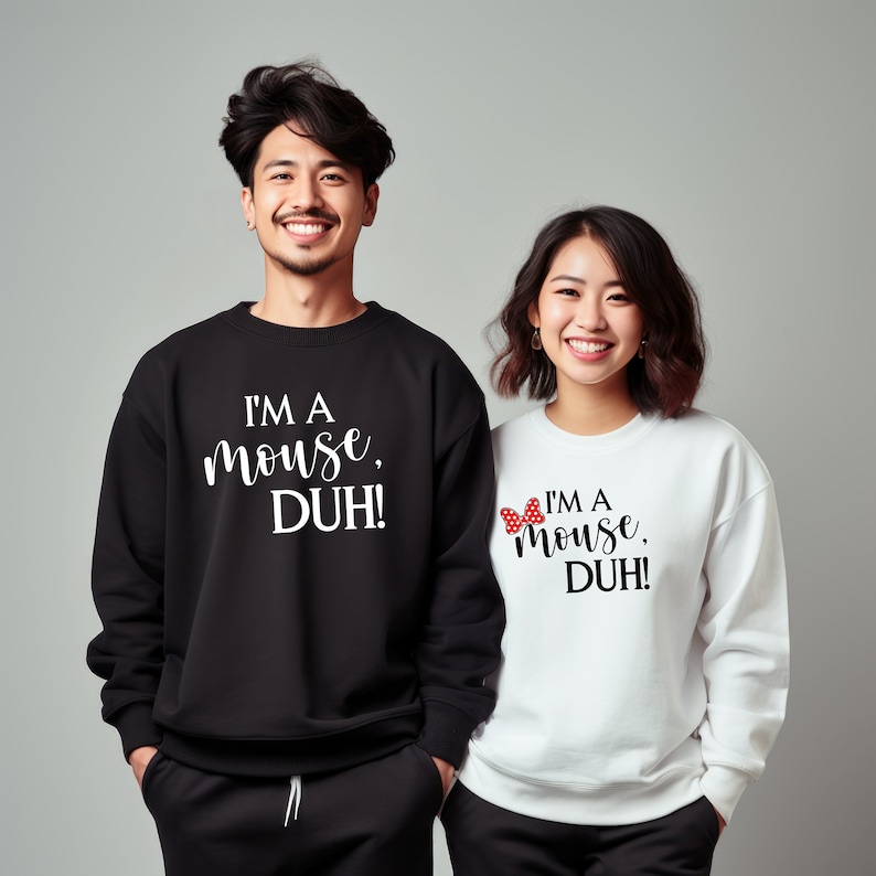 May include: Two people wearing black and white sweatshirts with the text "I'm a mouse, DUH!" on them. The woman's sweatshirt has a red and white bow on it.