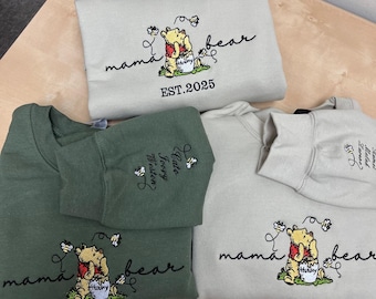 May include: Three sweatshirts with embroidered Winnie the Pooh designs. The green sweatshirt has the text "Mama Bear" and "Katie, Groovy, Winston" embroidered on it. The two beige sweatshirts have the text "Mama Bear" and "EST. 2025" embroidered on them.