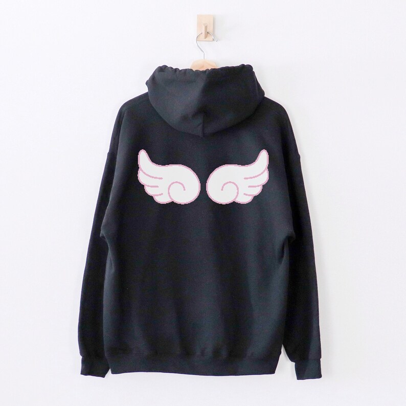 May include: Black hooded sweatshirt with a white angel wing design on the back. The wings have a pink outline.