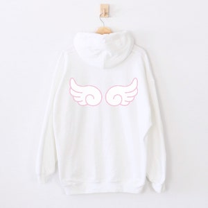 May include: White hooded sweatshirt with pink angel wings printed on the back.