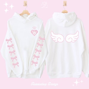 Könnte beinhalten: Weißer Hoodie mit einem pinkfarbenen, pixeligen Herzen mit einem WLAN-Symbol und einem Ein-/Ausschalter auf der Vorderseite. Die Ärmel haben rosa Schleifen. Die Rückseite des Hoodies hat rosa Engelsflügel.