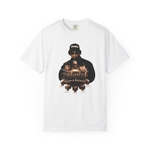 May include: White t-shirt featuring a graphic of a group of people with the text "Bone Thugs-n-Harmony" and the word "Compton" on the top. The graphic is in shades of black, brown, and tan.