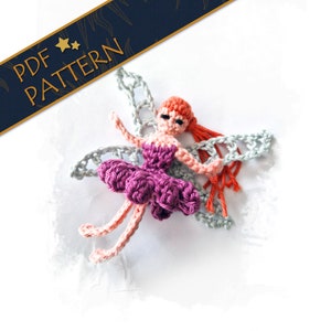 Może przedstawiać: Szydełkowa lalka wróżki z fioletową tutu, brzoskwiniowymi ramionami i nogami oraz pomarańczowymi włosami. Wróżka ma szare skrzydła i jest umieszczona na białym tle. Tekst "PDF PATTERN" znajduje się na granatowym banerze.