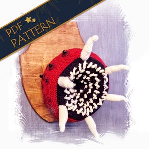 May include: A crocheted plush toy shaped like a mouth with teeth and tentacles. The toy is red, black, and white and is mounted on a wooden plaque. The toy is a replica of a creature from the video game "The Binding of Isaac".