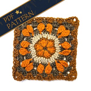 Pode incluir: Um motivo de crochê quadrado com uma flor laranja central cercada por anéis concêntricos de fio creme, cinza escuro e laranja. O design inclui pontos puff texturizados e uma faixa azul escura no topo com o texto PDF PATTERN.