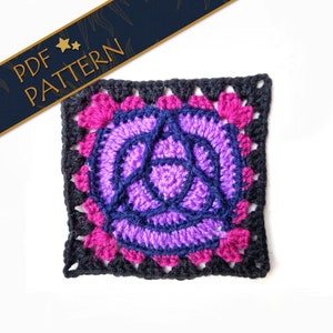 May include: A crochet square with a purple and blue triquetra design in the center. The triquetra is surrounded by a pink and black border.