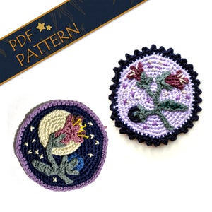 Può includere: Due motivi di fiori all'uncinetto, uno con sfondo viola e bordo blu scuro, l'altro con sfondo blu scuro e bordo viola. Entrambi i motivi presentano un fiore stilizzato con centro bianco e fiore rosa.