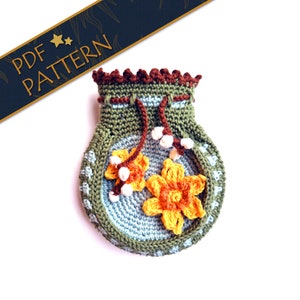 May include: A crocheted drawstring bag with a green body, blue and white interior, and yellow and orange flower accents. The bag has a brown crocheted trim around the top.