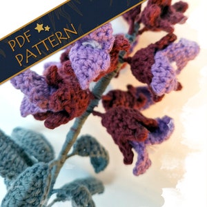 May include: Crochet pattern for a purple and burgundy flower with green leaves. The pattern is available as a PDF download.