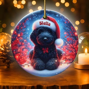 Capture the magic of the season with this adorable black Goldendoodle puppy wearing a festive Santa hat, surrounded by glowing red berries and twinkling snowflakes! Perfect personalized Christmas tree ornament for doodle parents. Add your dog's name (like "Stella") for a heartfelt touch. High-quality ceramic, vibrant print, gold string included. Ideal dog mom/dad gift, stocking stuffer, or memorial keepsake. Handmade holiday charm!