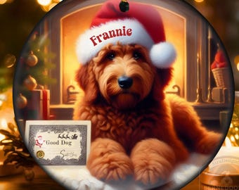 Könnte beinhalten: Runder Weihnachtsschmuck mit einem Golden Doodle, der einen Weihnachtsmannhut mit dem Namen "Frannie" trägt. Der Hund befindet sich vor einer Kaminlandschaft. Ein "Good Dog"-Zertifikat ist ebenfalls zu sehen. Der Schmuck hängt an einem goldenen Faden.