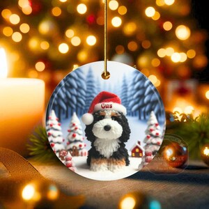 Bernedoodle claymation style ornament made of ceramic, hanging by a gold string.  Winter scene featuring a cute, personalized doodle dog with personalized name on santa hat.  Perfect gift for Bernedoodle Dog Lovers and Pet Enthusiasts.