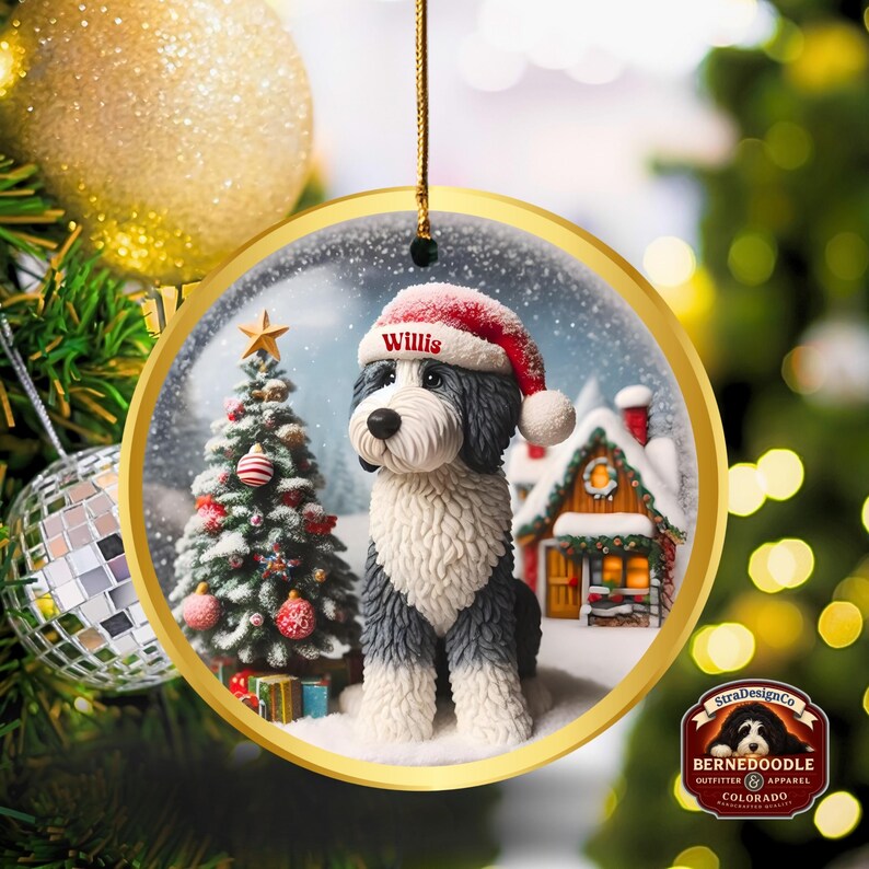 May include: A circular Christmas ornament with a gold edge, depicting a BerneDoodle dog in a Santa hat, with the name "Willis". The ornament shows a winter scene with a Christmas tree and a snow-covered house.