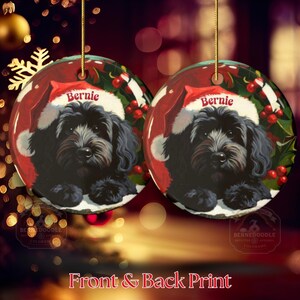 A black bernedoodle dog wearing a santa hat that is personalized with their name on it in this adorable Ceramic ornament!  Design appears on the front and the back of this doodle dog ornament!