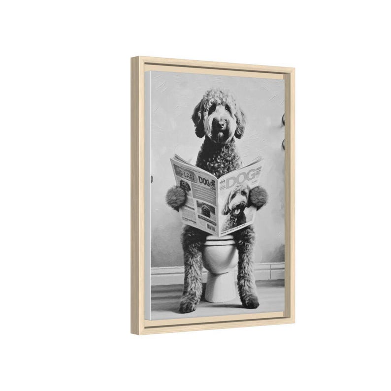 May include: A black and white framed wall art print featuring a curly-haired dog sitting on a toilet while reading a newspaper titled DOG. The dog has shaggy fur and is holding the open newspaper with both front paws in a vertical orientation.