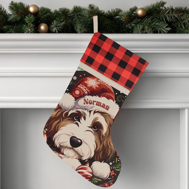 A festive Christmas stocking featuring a whimsical illustrated doodle dog wearing a red Santa hat, surrounded by holiday ornaments and greenery in a warm, detailed Christmas art style. The top of the stocking has a classic red and black buffalo-plaid cuff, and the stocking hangs from a white mantel decorated with evergreen garland and gold ornaments. The stocking design is personalized with your dog’s name, making it a charming and custom holiday décor piece for dog lovers.