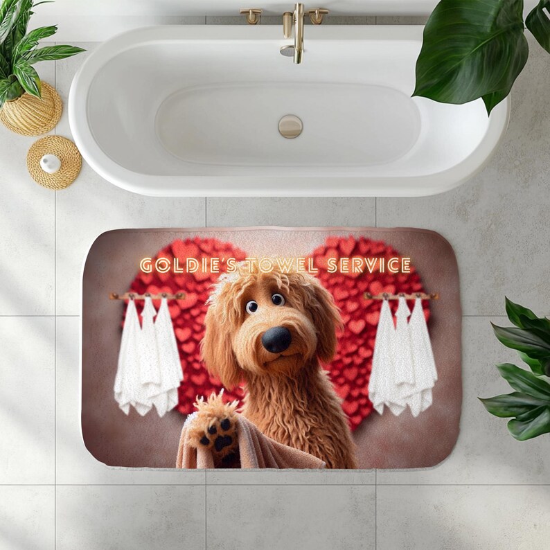 A cute golden doodle stands in front of a fluffy red heart backdrop, holding a brown towel on a cozy bath mat. White towels hang on either side, creating a spa-like feel. The text “Goldie’s Towel Service” sits above the doodle. Perfect for dog lovers, bathroom décor, and pet-themed home accents.