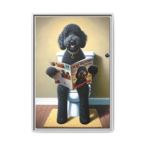 A humorous artwork features a fluffy black doodle-style dog with curly fur, sitting upright on a white toilet like a person, holding a dog magazine titled “Dog Ways to Score Better Treats.” The playful bathroom scene shows warm tan walls, a white baseboard, and wood flooring with a small beige rug under the dog’s feet. The dog gazes forward with a friendly expression, wearing a gold collar. The framed portrait blends realism and whimsy, making it perfect for bernedoodle and goldendoodle fans