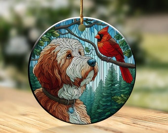 May include: A round ceramic ornament featuring a dog and a red cardinal bird. The dog has brown and white fur, a blue nose, and a collar. The cardinal is perched on a branch. The background includes a forest and blue sky.
