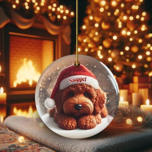 This ceramic ornament features a cute red mini-doodle golden doodle or goldendoodle dog wearing a Santa hat in a snow globe setting, surrounded by holiday decorations. Perfect for adding a festive touch to your Christmas tree or as a thoughtful gift for dog lovers.