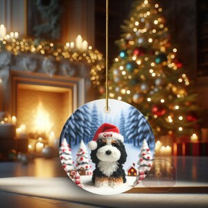 Bernedoodle claymation style ornament made of ceramic, hanging by a gold string.  Winter scene featuring a cute, personalized doodle dog with personalized name on santa hat.  Perfect gift for Bernedoodle Dog Lovers and Pet Enthusiasts.