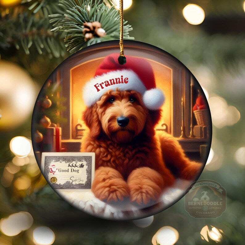 Pu&ograve; includere: Ornamento natalizio rotondo con un golden doodle con un cappello da Babbo Natale con il nome "Frannie". L'ornamento ha un certificato che dice "Good Dog". Lo sfondo mostra un camino e decorazioni natalizie.