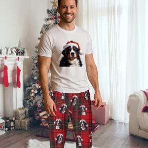 A man seen wearing Men's pajama pants lounge wear personalized Christmas pajama bottoms with Bernese Mountain dogs wearing Santa Hat and their name is on the Santa Hat.  Bernese Mountain Dog dad gear!