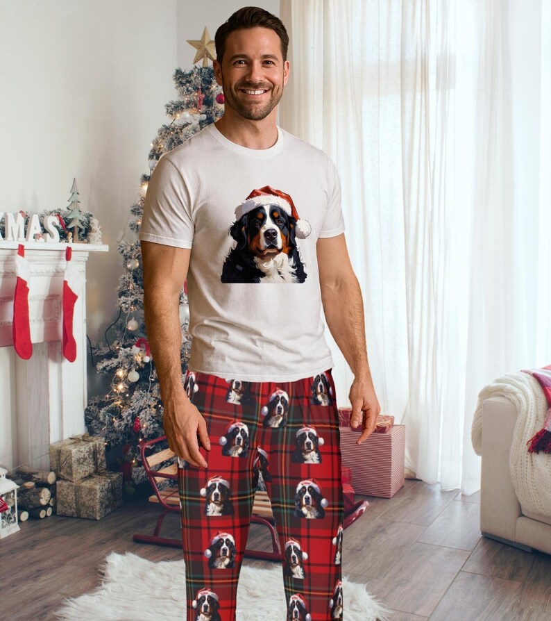 A man seen wearing Men's pajama pants lounge wear personalized Christmas pajama bottoms with Bernese Mountain dogs wearing Santa Hat and their name is on the Santa Hat.  Bernese Mountain Dog dad gear!