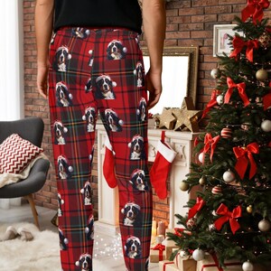 A man seen wearing Men's pajama pants lounge wear personalized Christmas pajama bottoms with Bernese Mountain dogs wearing Santa Hat and their name is on the Santa Hat.  Bernese Mountain Dog dad gear!