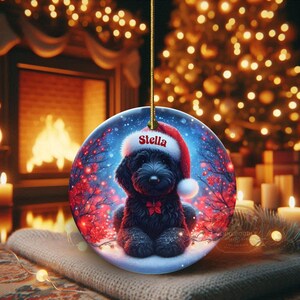 Capture the magic of the season with this adorable black Goldendoodle puppy wearing a festive Santa hat, surrounded by glowing red berries and twinkling snowflakes! Perfect personalized Christmas tree ornament for doodle parents. Add your dog's name (like "Stella") for a heartfelt touch. High-quality ceramic, vibrant print, gold string included. Ideal dog mom/dad gift, stocking stuffer, or memorial keepsake. Handmade holiday charm!