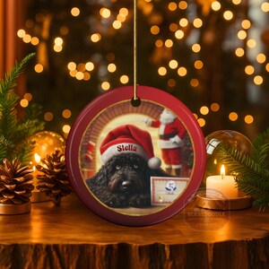 This ceramic ornament features a cute black goldendoodle (or Labradoodle)...Or black bernedoodle dog wearing a Santa hat and being on their best behavior for Santa, surrounded by holiday decorations.  Three inch ceramic dog ornament with a black bernedoodle black golden doodle black goldendoodle dog wearing a santa hat on this cute dog ornament gift.  Perfect ornament for a dog person, dog lover, doodle mom or doodle dad.