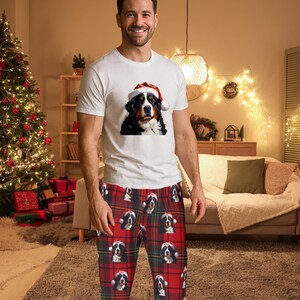 A man seen wearing Men's pajama pants lounge wear personalized Christmas pajama bottoms with Bernese Mountain dogs wearing Santa Hat and their name is on the Santa Hat.  Bernese Mountain Dog dad gear!