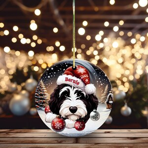 Personalize your holiday decor with this charming Bernedoodle Christmas ornament! Featuring a cute Bernedoodle in a festive Santa hat and customizable name, this round ornament adds warmth and joy to any tree. Perfect for dog lovers and unique gifts!