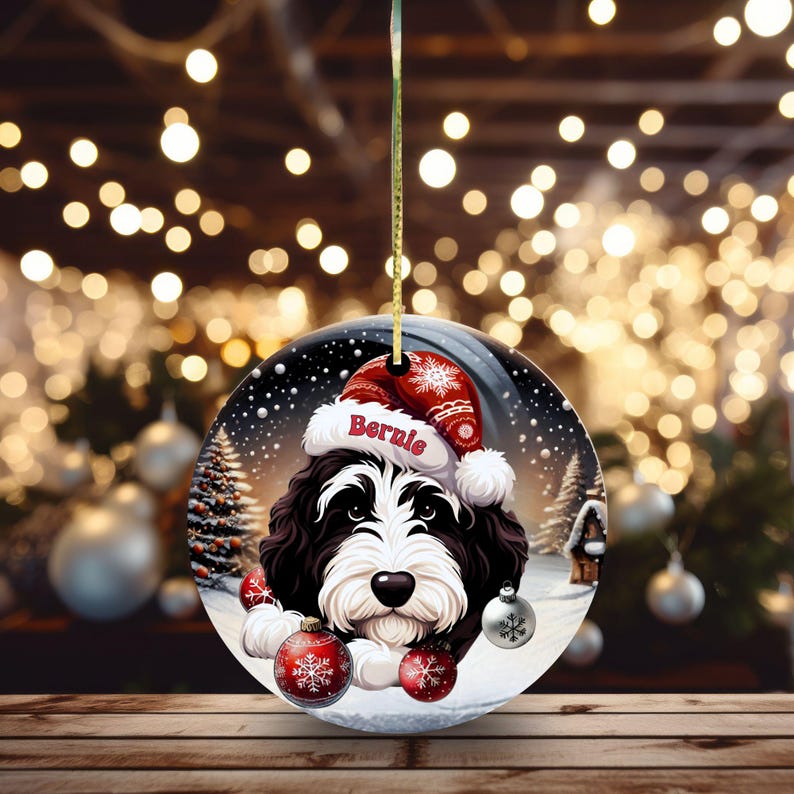 Personalize your holiday decor with this charming Bernedoodle Christmas ornament! Featuring a cute Bernedoodle in a festive Santa hat and customizable name, this round ornament adds warmth and joy to any tree. Perfect for dog lovers and unique gifts!