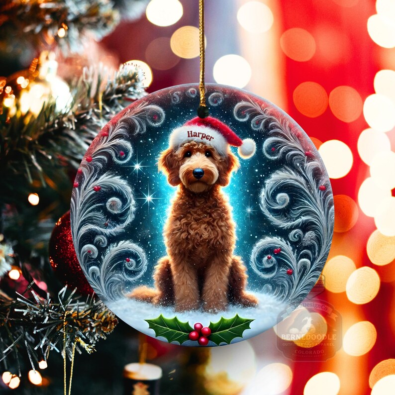 This personalized Christmas ornament highlights a fluffy goldendoodle posed on snowy ground with a Santa hat that reads “Harper.” Decorative swirls, starry night textures, and holly elements frame the dog. Warm blurred lights behind the ornament enhance the cozy winter atmosphere. Great keepsake for dog parents and holiday décor.