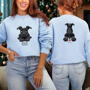 Puede incluir: Sudadera azul claro con un dise&ntilde;o de perro negro y el nombre "KENZIE" debajo. La parte trasera de la sudadera muestra una vista trasera del perro con un coraz&oacute;n y las palabras "dog mom".