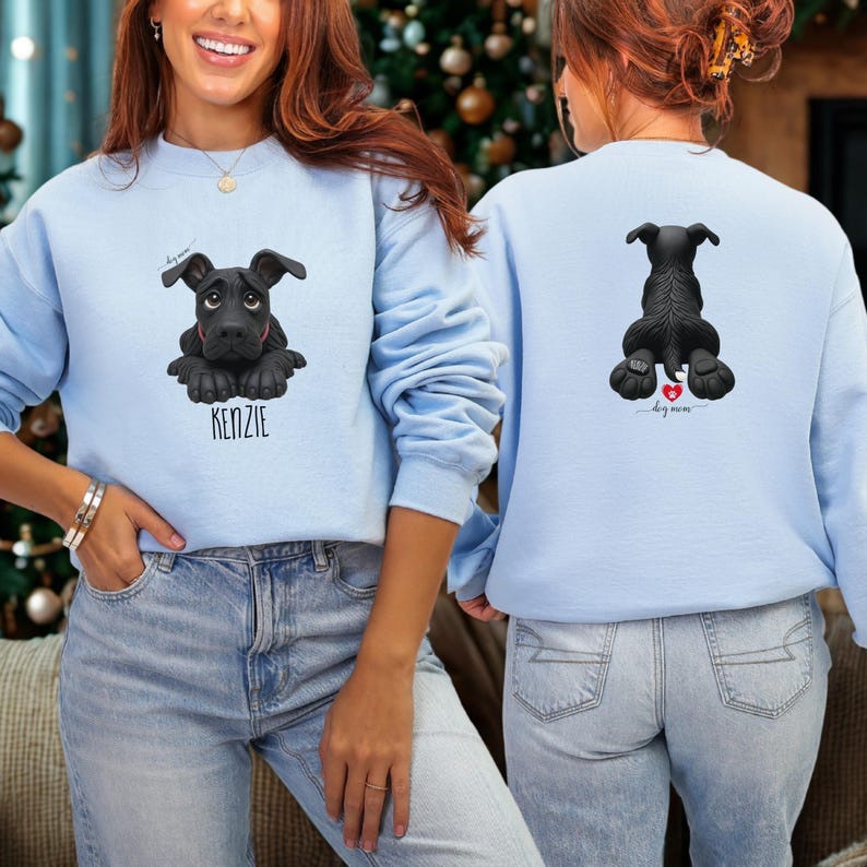 Puede incluir: Sudadera azul claro con un dise&ntilde;o de perro negro y el nombre "KENZIE" debajo. La parte trasera de la sudadera muestra una vista trasera del perro con un coraz&oacute;n y las palabras "dog mom".