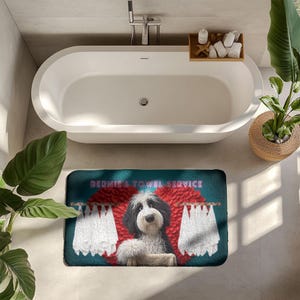 May include: A teal bath mat featuring a cartoon dog with black and white fur, red accents, and two white towels hanging on a clothesline. The text "BERNIE'S TOWEL SERVICE" is displayed on the mat.