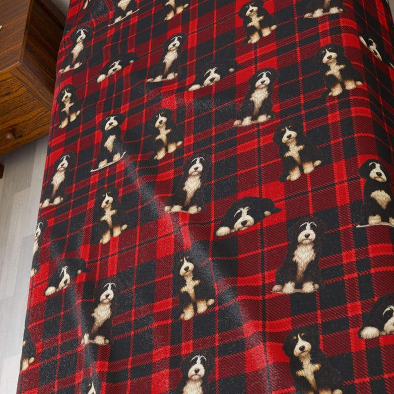 Peut inclure: Un tissu &agrave; carreaux rouge et noir pr&eacute;sentant un motif r&eacute;p&eacute;titif de petits chiots bouviers bernois noirs et blancs, dans diverses positions assises et couch&eacute;es, r&eacute;partis uniform&eacute;ment sur la surface textile.