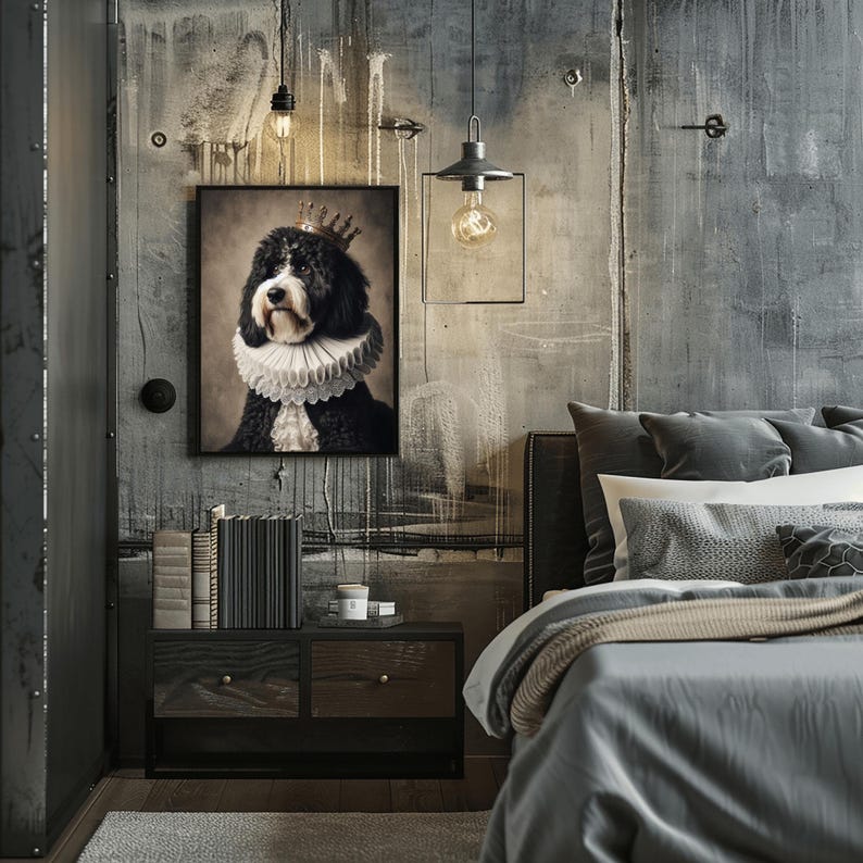May include: A framed portrait of a black and white dog wearing a crown and ruffled collar hangs above a nightstand in a bedroom. The nightstand has two drawers and a stack of books. A bed with gray bedding is in the foreground.