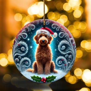 A cozy Christmas ornament featuring a goldendoodle sitting in fluffy snow while wearing a Santa hat with the name “Harper.” Frosty feather-style swirls, glittering stars, and holly berries add decorative flair. The glowing background lights create warmth and charm, making it ideal as a personalized gift or tree decoration.