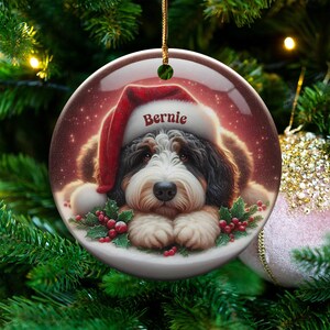 Personalize your holiday decor with this charming Bernedoodle Christmas ornament! Featuring a cute Bernedoodle in a festive Santa hat and customizable name, this round ornament adds warmth and joy to any tree. Perfect for dog lovers and unique gifts!