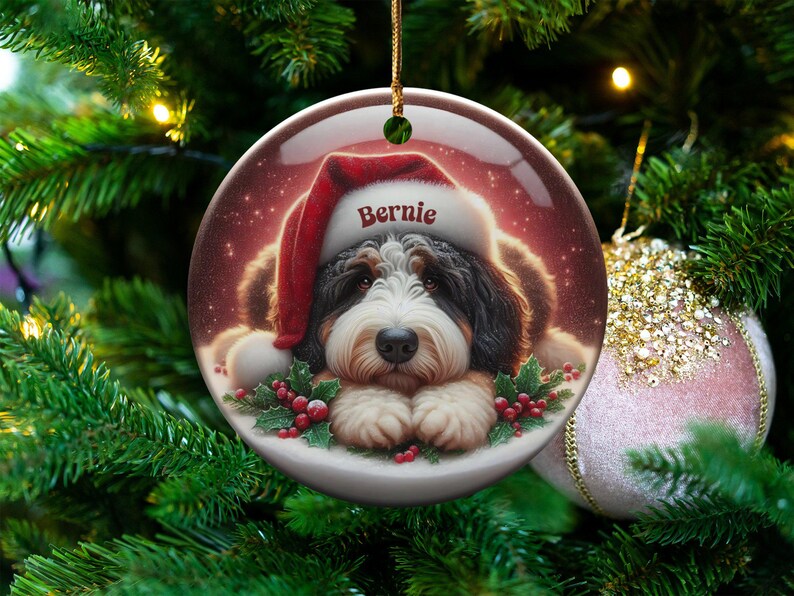 Personalize your holiday decor with this charming Bernedoodle Christmas ornament! Featuring a cute Bernedoodle in a festive Santa hat and customizable name, this round ornament adds warmth and joy to any tree. Perfect for dog lovers and unique gifts!