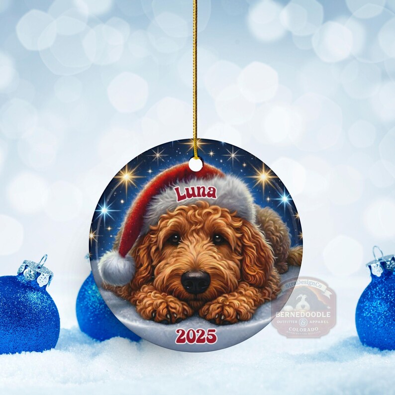 A ceramic ornament of a goldendoodle dog wearing a Santa hat, personalized with the dog's name and the year.  Gorgeously placed in a warm background with candles and Christmas lights.