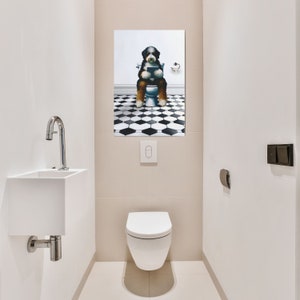 May include: A rectangular wall art print featuring a black, white, and brown Bernese Mountain Dog sitting on a white toilet while reading a book. The background of the artwork shows a black and white hexagonal tiled floor and a white wall.