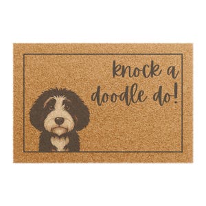 May include: A rectangular doormat with a brown background and a black border. The mat features a black and white dog illustration on the left and the phrase "knock a doodle do!" in black script on the right.