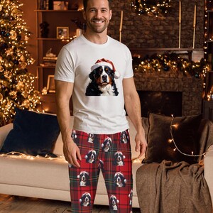 A man seen wearing Men's pajama pants lounge wear personalized Christmas pajama bottoms with Bernese Mountain dogs wearing Santa Hat and their name is on the Santa Hat.  Bernese Mountain Dog dad gear!