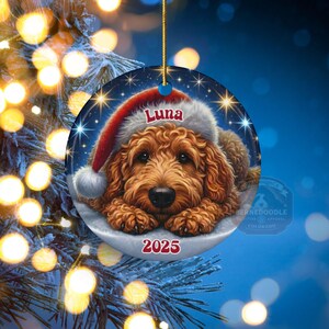 A ceramic ornament of a goldendoodle dog wearing a Santa hat, personalized with the dog's name and the year.  Gorgeously placed in a warm background with candles and Christmas lights.