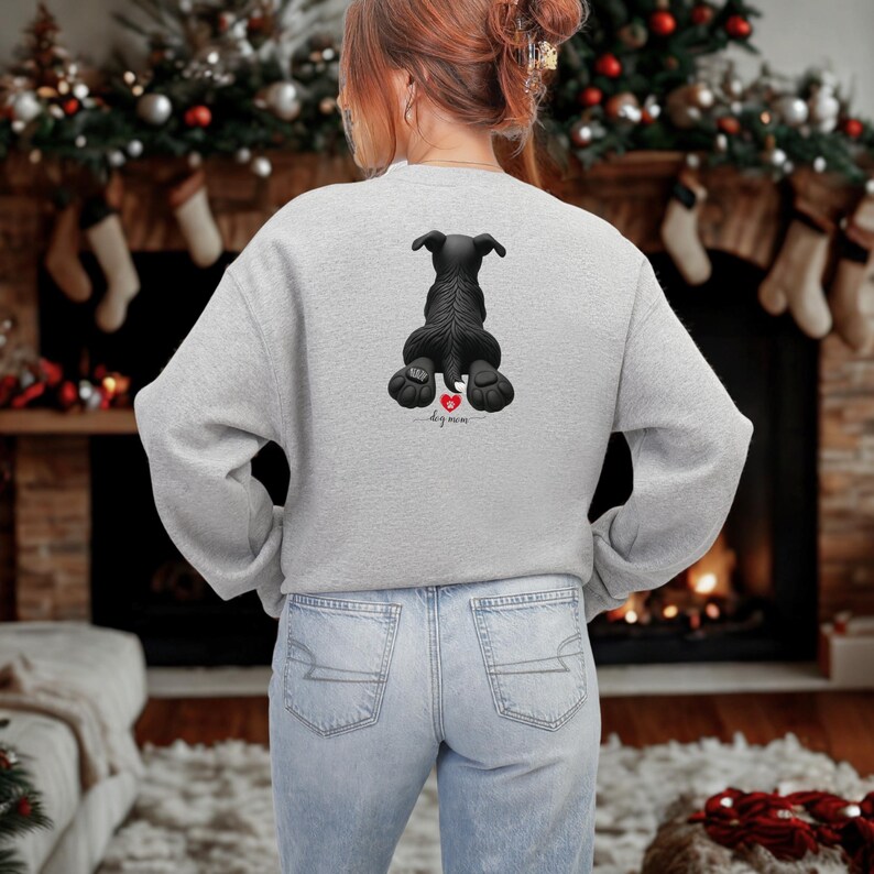 Puede incluir: Sudadera gris claro con un gr&aacute;fico de perro negro, un coraz&oacute;n rojo y las palabras "dog mom". La sudadera est&aacute; hecha de un material suave y es ideal para los amantes de los perros.
