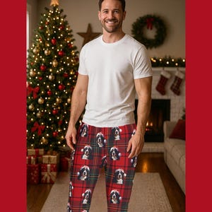 A man seen wearing Men's pajama pants lounge wear personalized Christmas pajama bottoms with Bernese Mountain dogs wearing Santa Hat and their name is on the Santa Hat.  Bernese Mountain Dog dad gear!